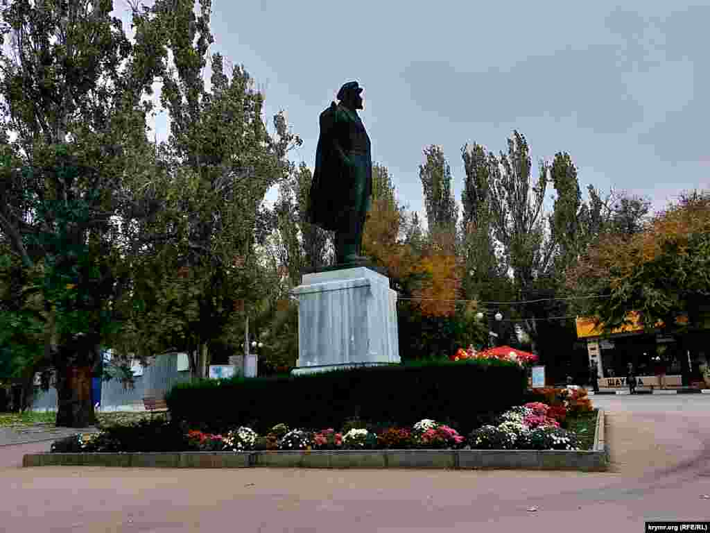 Різнобарвне листя на деревах і квіти на клумбі біля пам'ятника Леніну в Феодосії – останні барви осені в Криму
