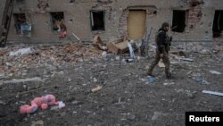 Un soldat ucrainean lângă o clădire distrusă din orașul Ceasov Iar. Martie 2023