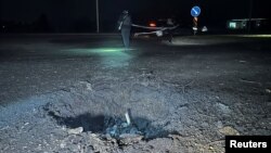 Polițiști în apropierea unui crater produs de un atac rusesc cu drone asupra Harkovului.
