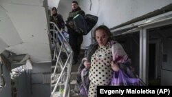 Поранена вагітна жінка йде вниз у пошкодженому від авіаційного удару російських військових пологовому будинку в Маріуполі, 9 березня 2022 року