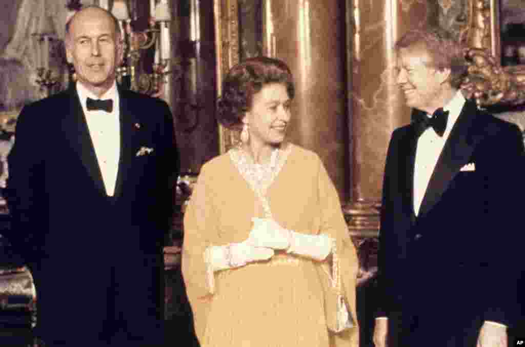 Президент США Джиммі Картер (праворуч) та королева Єлизавета II фотографуються з президентом Франції Валері Жискаром д'Естеном у Букінгемському палаці у Лондоні у травні 1977 року