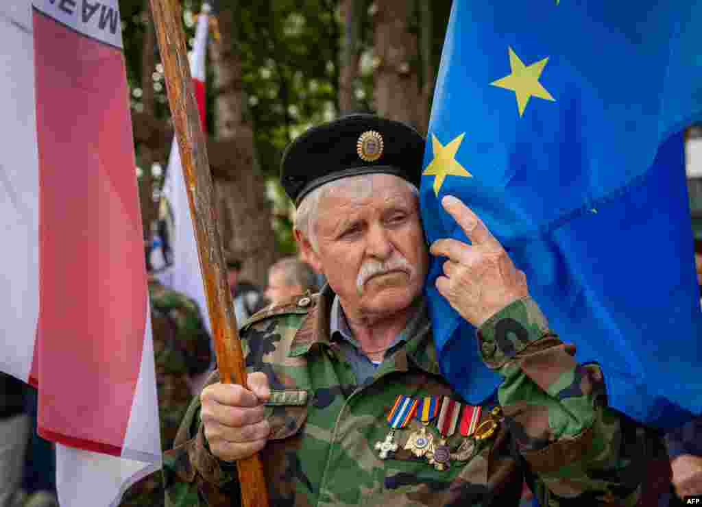 Un veteran al armatei moldovenești atinge drapelul UE în timpul unei ceremonii în cinstea militarilor care au luptat în cel de-al Doilea Război Mondial, la care au participat și autoritățile centrale ale Republicii Moldova, în cadrul ceremoniei Zilei Victoriei celui de-al Doilea Război Mondial și Zilei Europei, la Chișinău, pe 9 mai 2024. 