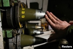 Un militar ucrainean fixează un obuz de 155 mm într-o țeavă de obuzier autopropulsat în apropierea orașului ucrainean devastat Bahmut, pe 16 ianuarie 2024.