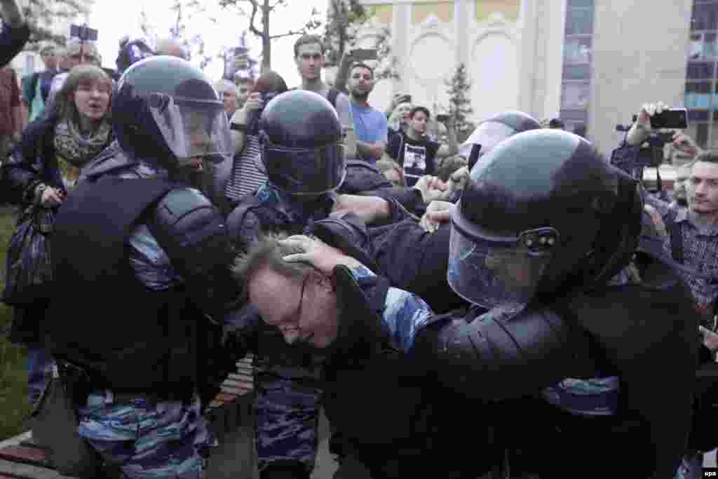 Полицейский спецназ забирает участника акции в Москве.