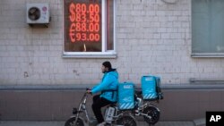 Moskvada yemək çatdırılma kuryeri valyutadəyişmə məntəqəsinin qarşısından keçir.