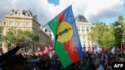 Un protestatar Kanak flutură un steag al Frontului Național de Eliberare Națională în timpul unui protest din 16 mai 2024.
